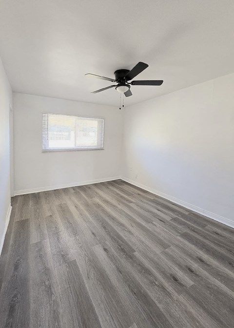 A room with a ceiling fan and a window with blinds.