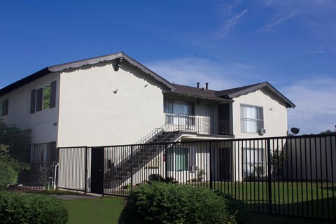 A white house with a black fence and a green lawn in front.