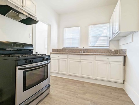 A black stove top oven in a kitchen with white cabinets.