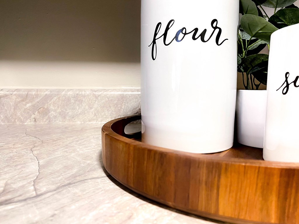 a white cylinder cylinder on a wooden tray with plants