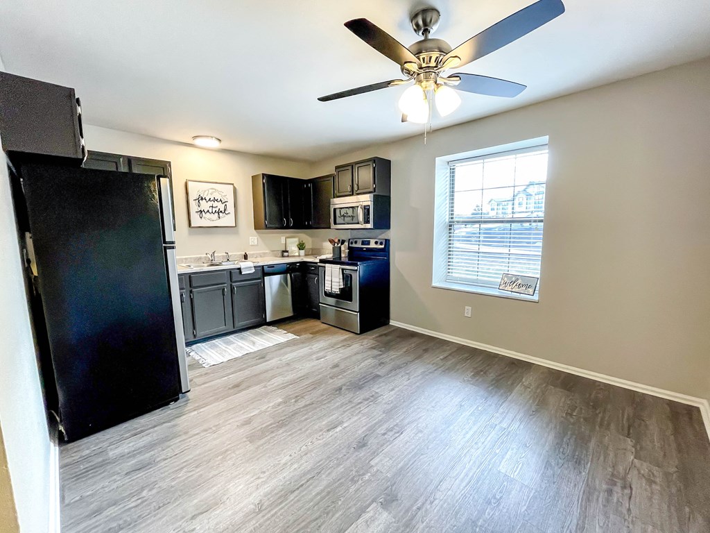 a kitchen with black appliances and a ceiling fan