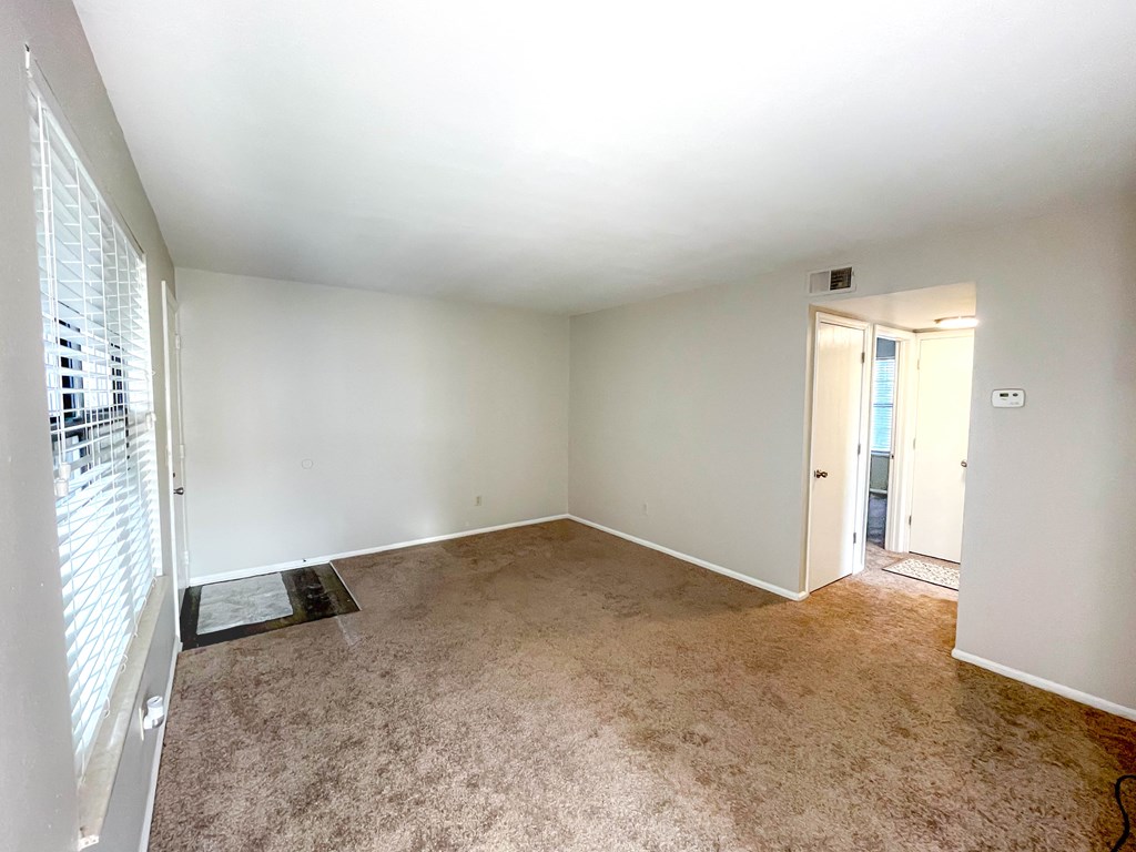 an empty living room with white walls and beige carpet