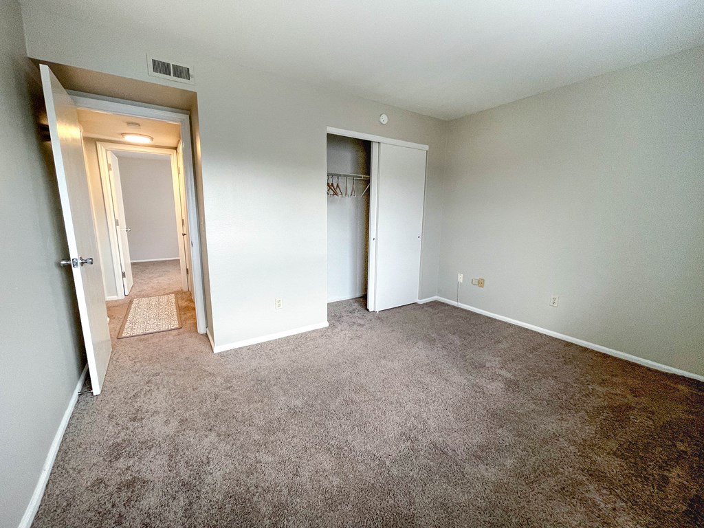 an empty living room with carpeting and a door to a hallway