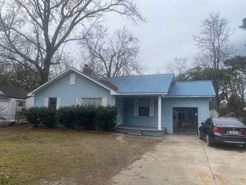 A blue house with a car parked in front.