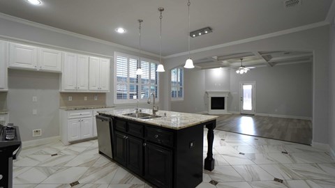 A kitchen with black cabinets and a marble countertop.