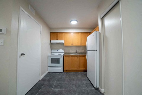 A kitchen with a white refrigerator, white oven, and white microwave.