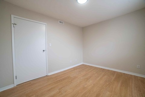 A room with a white door and wooden floor.