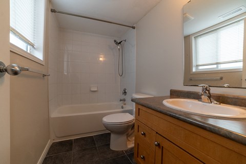 A white toilet sits in a bathroom next to a sink and a bathtub.