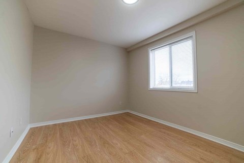 A room with wooden flooring and a window with blinds.