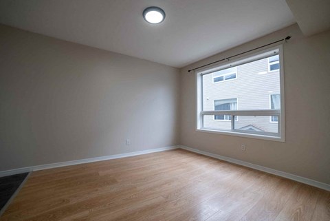 A room with a window and a wooden floor.