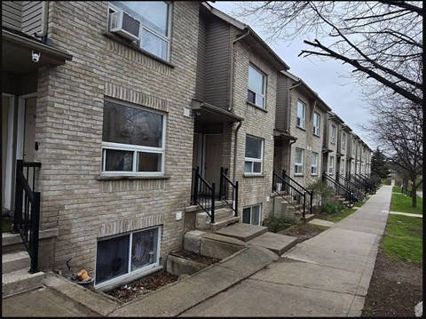 A row of houses with a sidewalk in front.
