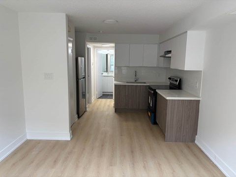 A kitchen with a refrigerator, oven, and sink.