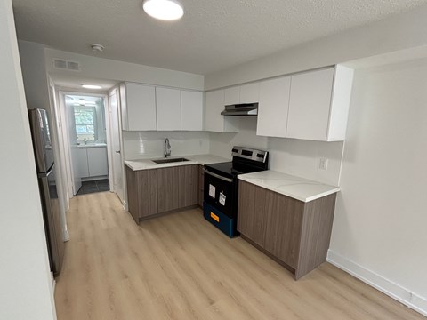 A kitchen with white cabinets and a wooden floor.