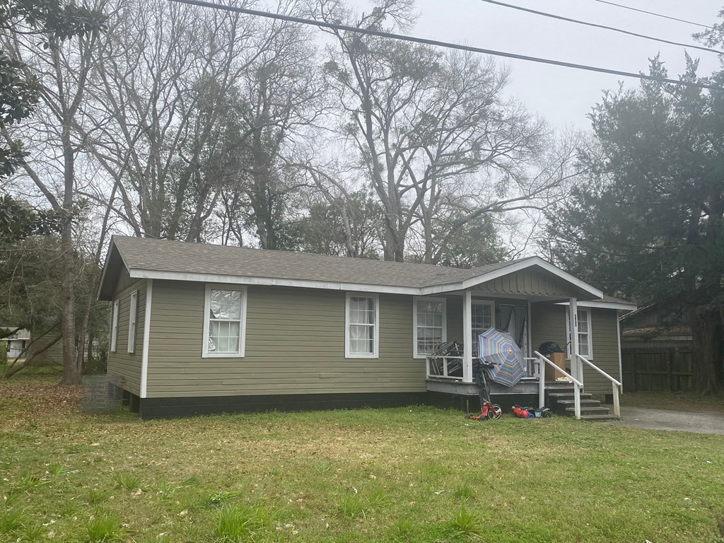 A small house with a porch and a lawn in front.