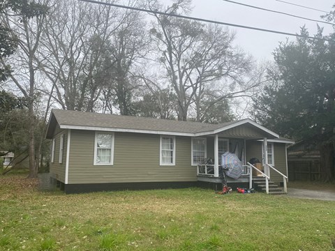 A small house with a porch and a lawn in front.