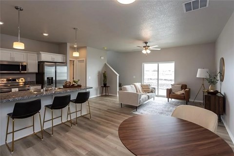 A modern kitchen with a bar area and a living room with a couch and chairs.