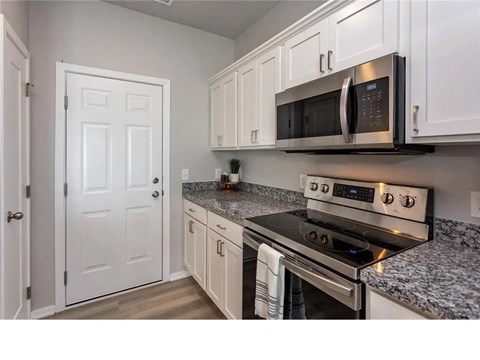 A kitchen with a stove, microwave, and cabinets.