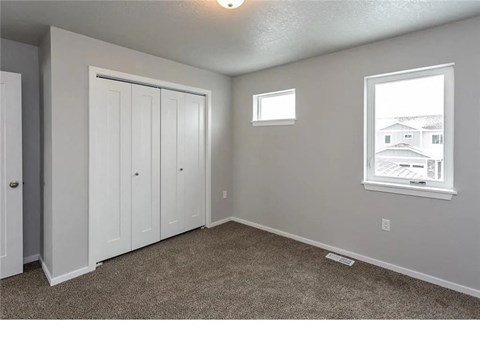 A room with a carpeted floor, a window, and a door.