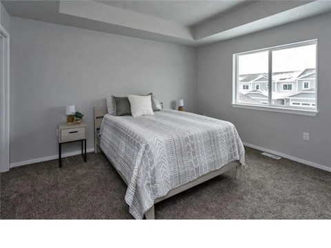 A bedroom with a large bed and a window showing a view of houses.