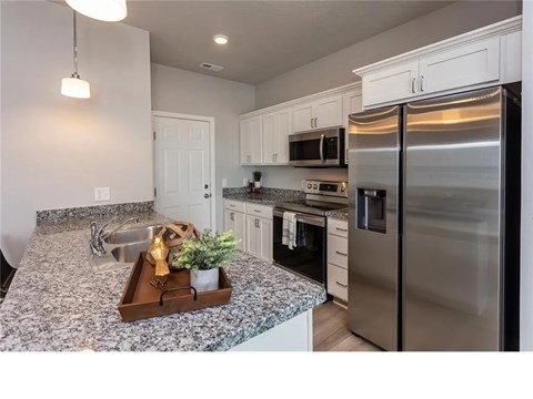 A kitchen with a granite countertop and stainless steel appliances.