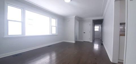 an empty living room with white walls and a wooden floor