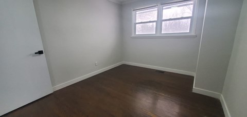 a room with white walls and a window and wooden floors