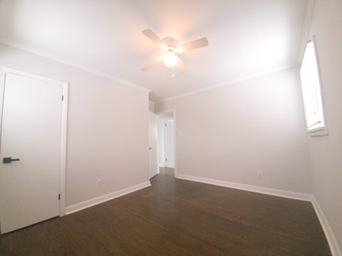 a bedroom with a ceiling fan and white walls