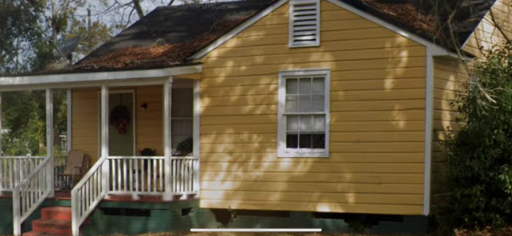 A yellow house with a white porch.