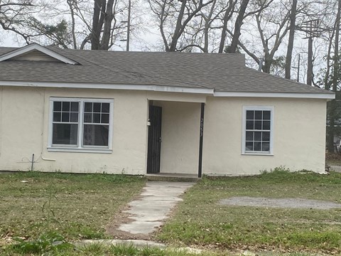 a small white house with a sidewalk in front of it