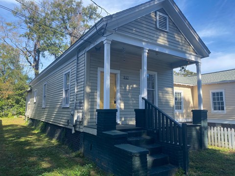 A small house with a front porch and stairs leading up to it.