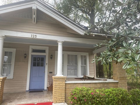 the front of a house with a porch and a blue door