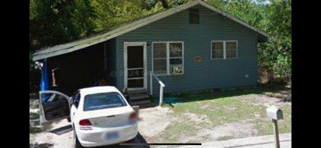 a white car parked in front of a blue house