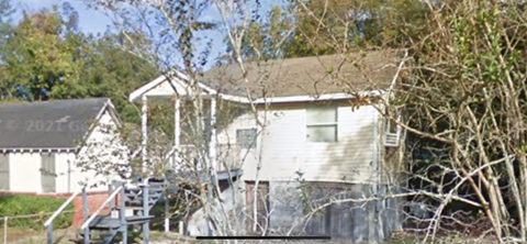 A house with a porch and a tree in front.