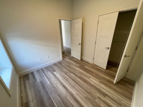 a bedroom with wood flooring and a closet