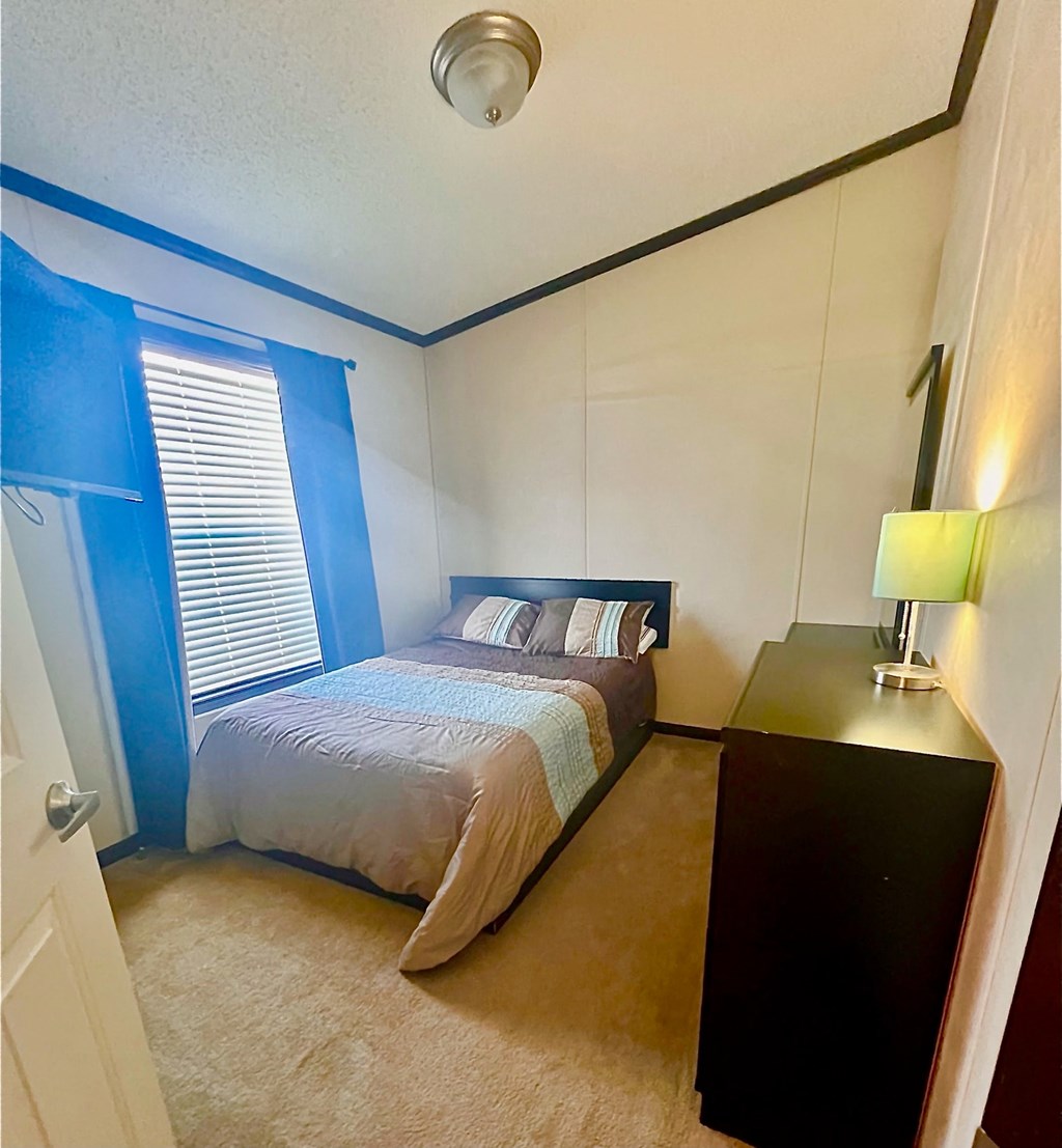 a bedroom with a bed and a dresser and a window