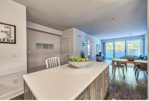 A kitchen with a white counter and a bowl of fruit on it.