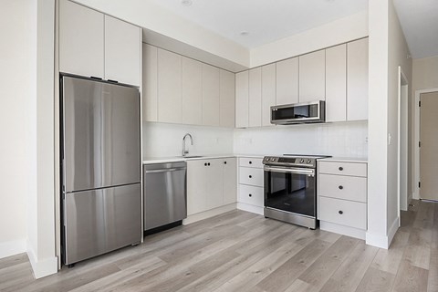 a white kitchen with stainless steel appliances and white cabinets