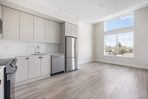 an empty kitchen with white cabinets and a large window