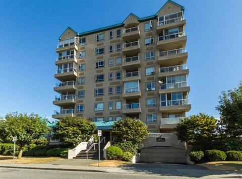 A large apartment building with a green roof and a staircase leading to the entrance.