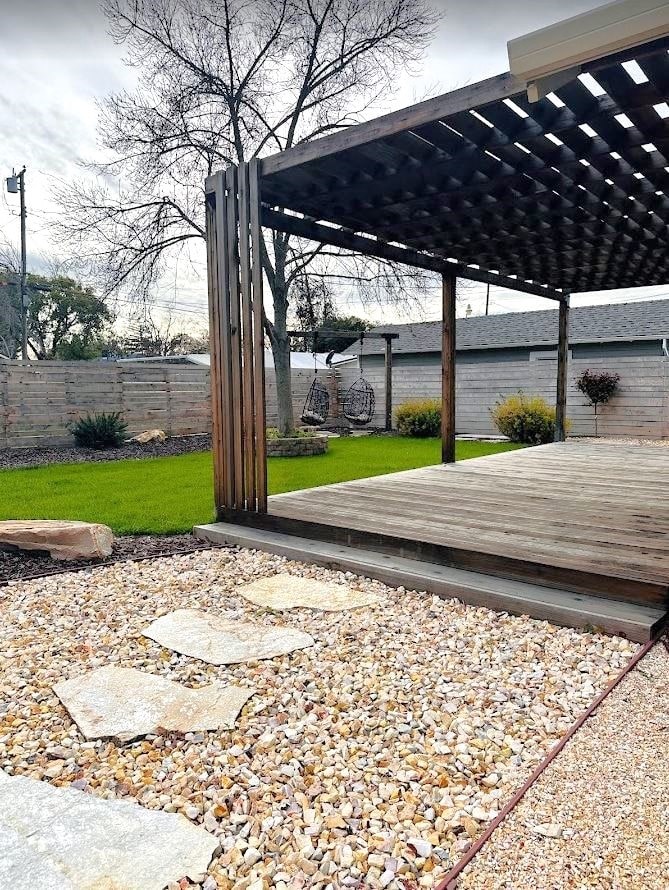 a backyard with a wooden deck and a pergola