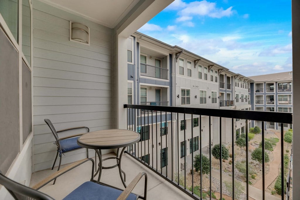 a balcony with a table and chairs in front of a building