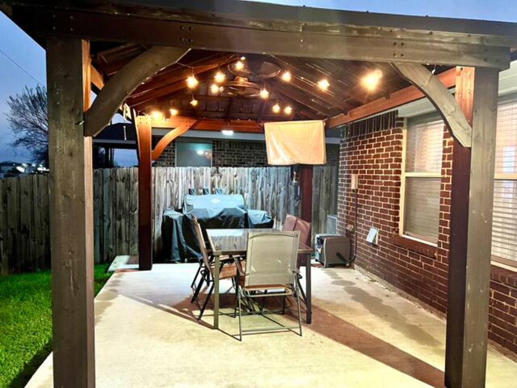 a patio with a table and chairs and lights on it