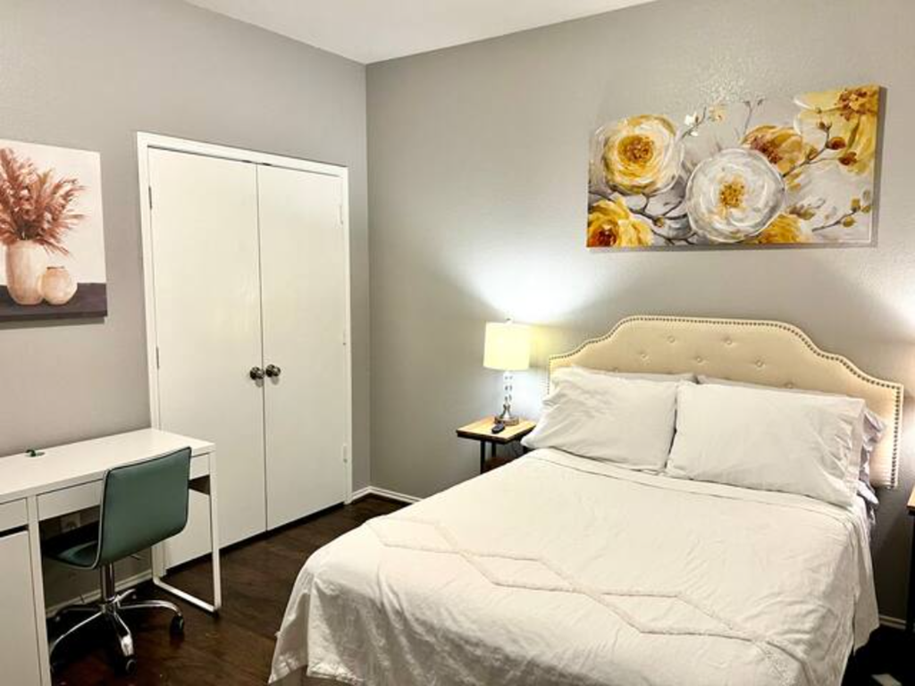 a bedroom with a white bed and a desk