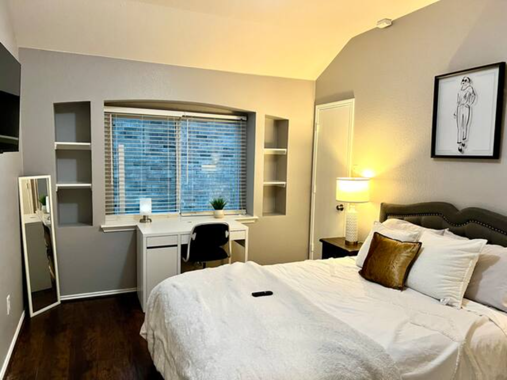 a bedroom with a bed and a desk and a window