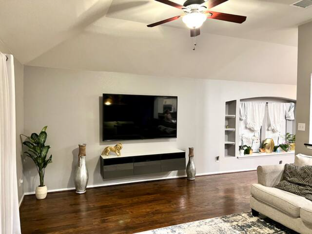 a living room with a ceiling fan and a television