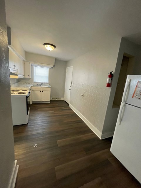 A kitchen with white appliances and wooden floors.