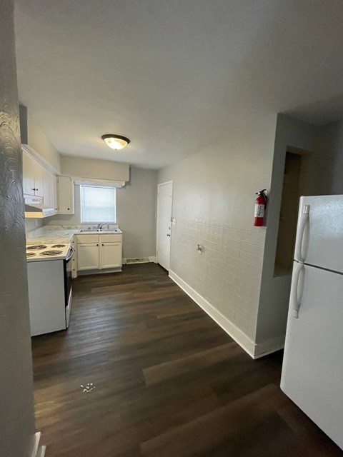 A kitchen with white appliances and wooden floors.