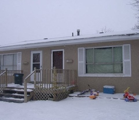 A house with a brown and white exterior is surrounded by snow.
