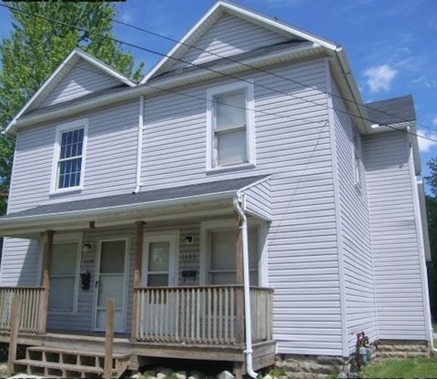 A small house with a porch and a white door.