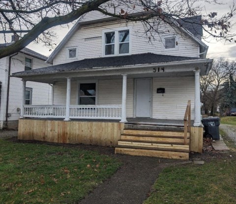 a white house with a porch and a wooden fence